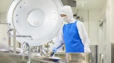 エプロンとゴム手袋をしてボウルを持つA.K.さん